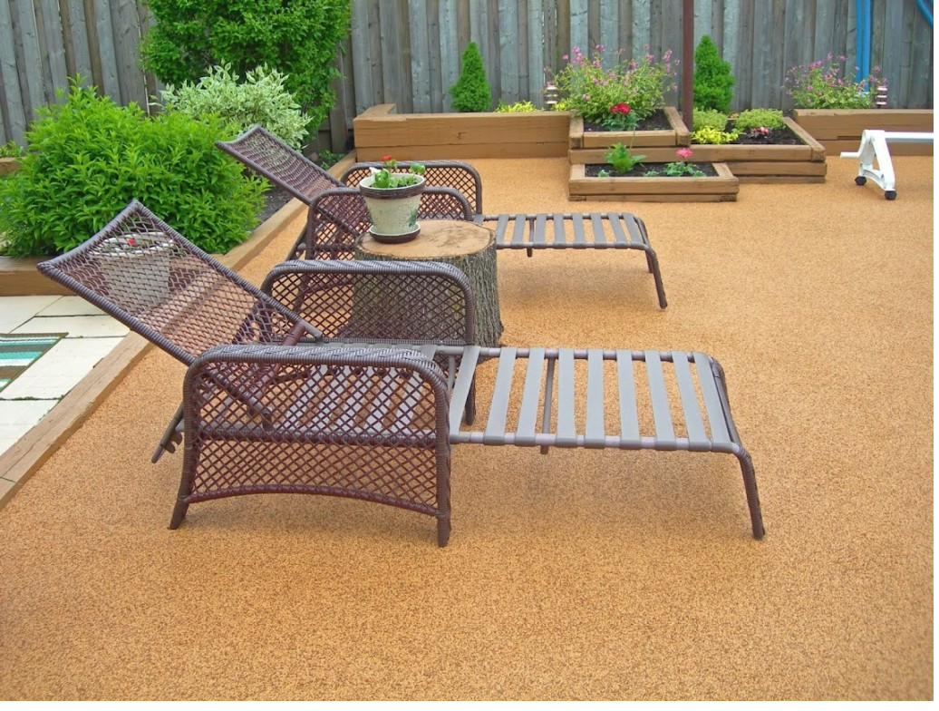 Tan poured rubber patio with lounge chairs and a fire pit