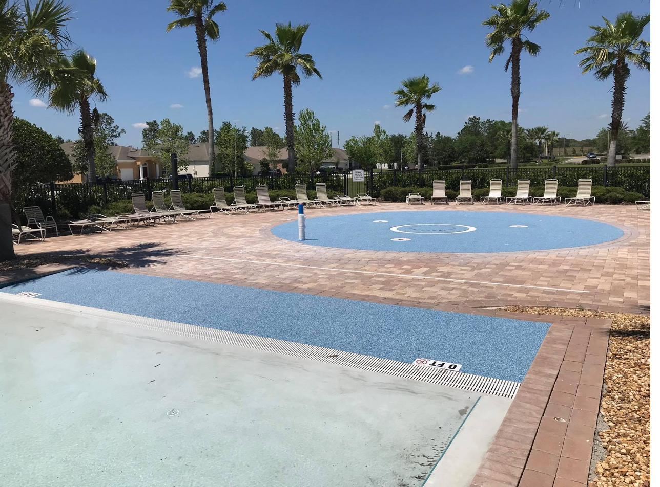 Blue poured rubber surfacing around a community pool deck with palm trees